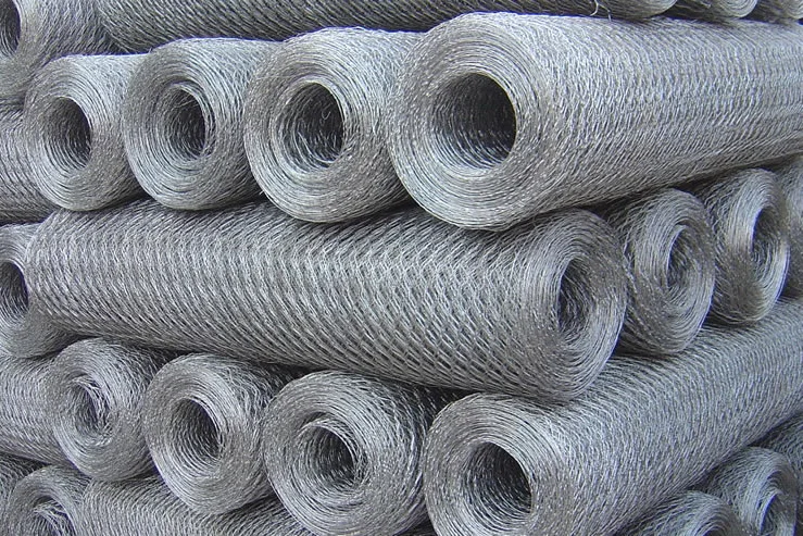 Rolos de tela hexagonal galvanizada empilhados, com a trama em favo característica visível nas pontas